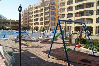 a playground in front of a pool with people playing at Apartament Aheloy in Aheloy
