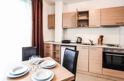 a kitchen with a wooden table with chairs and a dining room at NLV Seaside Apartments in Sunny Beach