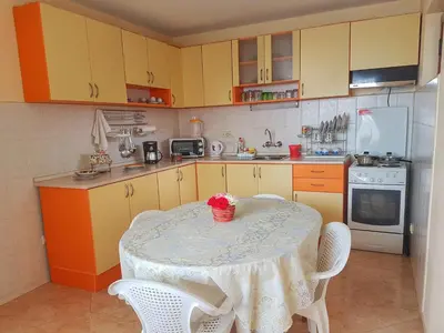 a kitchen with a table and chairs and a kitchen with yellow cabinets at Guest House Byki in Sveti Vlas
