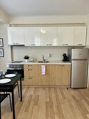 a kitchen with white cabinets and a sink and a table at Apartments Flora 1 in Burgas City