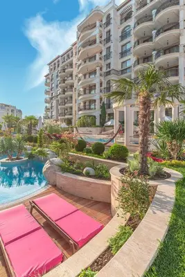 a large apartment building with pink yoga mats next to a swimming pool at Harmony Suites Apartment in Sveti Vlas