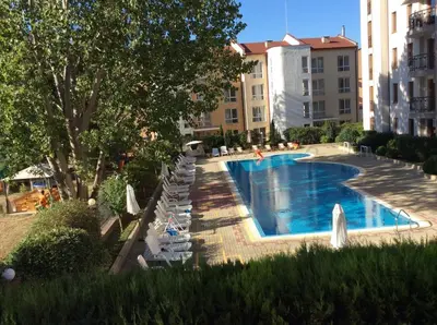 a large swimming pool with white chairs and a building at Alex Deluxe Apartments in Sunny Beach