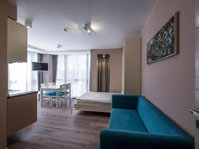a living room with a blue couch and a bed at Caro Apartments & Rooms in Varna City
