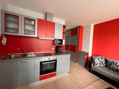 a kitchen with red walls and a couch in a room at Sirena Holidays in Ravda