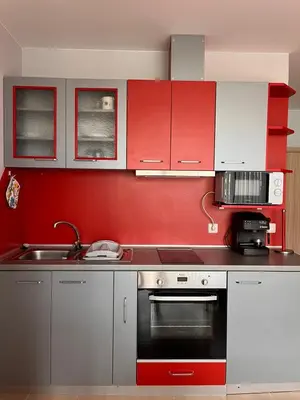 a kitchen with red and white cabinets and a sink at Sirena Holidays in Ravda