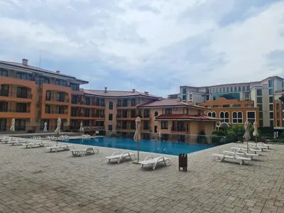 a pool with chairs and umbrellas in a courtyard at Private Apartment in Star Dreams Complex in Sveti Vlas