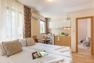 a living room with a white couch and a kitchen at Apartments Flora in Burgas City