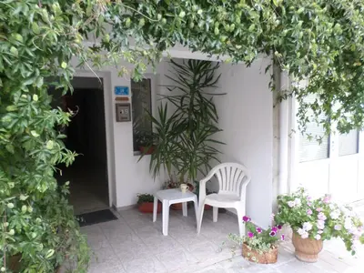 two white chairs sitting on a porch with plants at Rooms Via Maris in Sozopol