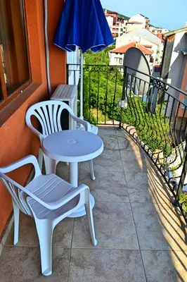 a patio with two chairs and a table and an umbrella at Joro Guest House in Sveti Vlas