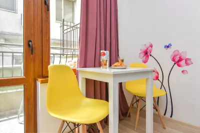 a table and yellow chairs in a room at The Cozy Apartment in Varna City