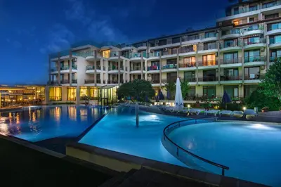 a hotel with a large swimming pool at night at Aparthotel Hotel Prestige City II in Primorsko