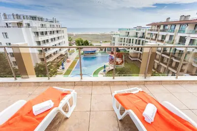 a balcony with a view of a pool and buildings at Aparthotel Hotel Prestige City II in Primorsko