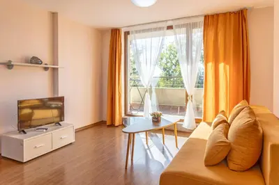 a living room with a couch and a tv and a window at Aparthotel Hotel Prestige City II in Primorsko