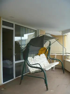 a green bench on a balcony with a bed at Apartments Lucky Complex Ravda in Ravda