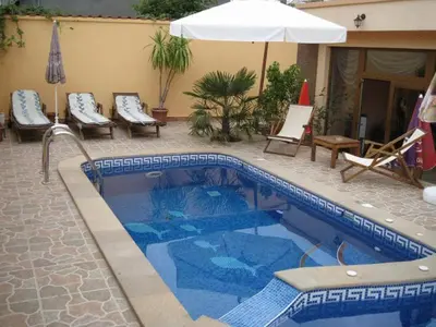 a swimming pool with chairs and an umbrella at Family Hotel Hit in Kiten