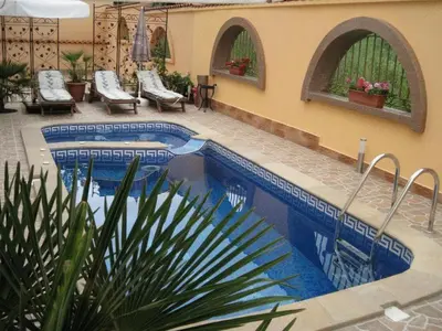 a swimming pool in a patio with chairs next to a building at Family Hotel Hit in Kiten