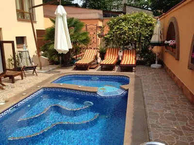 a swimming pool with chairs and an umbrella at Family Hotel Hit in Kiten