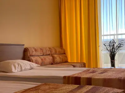 a bedroom with a bed and a window with yellow curtains at Hotel Plamena Palace in Primorsko