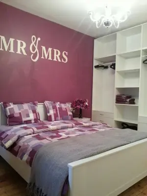 a bedroom with a large bed with a purple wall at Florata apartment in Burgas City