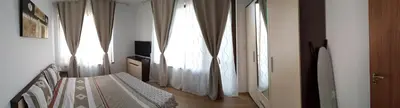 a bedroom with white curtains and a bed and a television at Boulevard Sea Residence in Sunny Beach