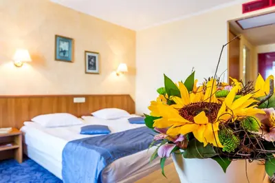 a hotel room with a bed and a bouquet of flowers at Saint George Hotel & Medical Spa in Pomorie