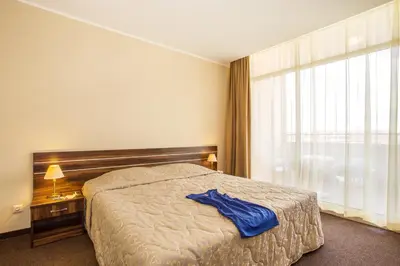 a bedroom with a bed with a blue shirt on it at Hotel Laguna Park & Aqua Club - All Inclusive in Sunny Beach