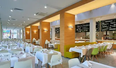 a dining room with white tables and chairs at Hotel Laguna Park & Aqua Club - All Inclusive in Sunny Beach