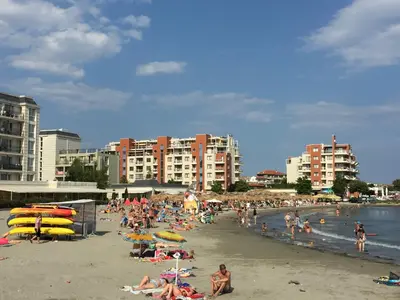 a group of people on a beach with buildings at Apartments Helios in Pomorie
