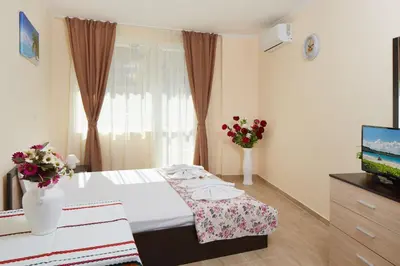 a bedroom with a bed and a television and flowers at Feniks Apartments in Nesebar