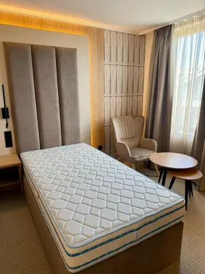 a bedroom with a bed and a chair and a table at Hotel Luxor in Burgas City