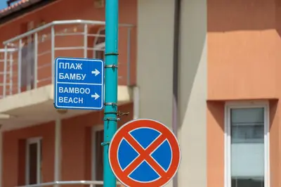 a blue street sign on a pole with a no parking sign at Apartment Sea Shell 1 in Sozopol