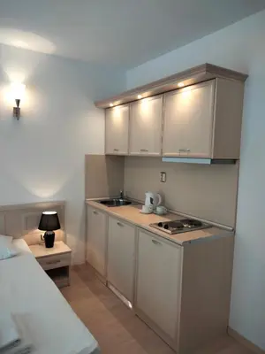 a small kitchen with white cabinets and a bed at Avalon Apartament in Sunny Beach