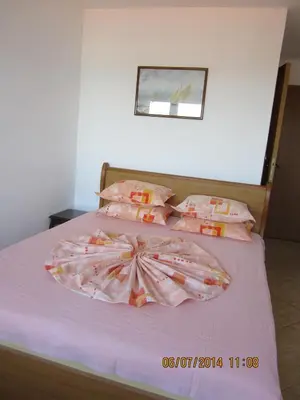 a bedroom with a bed with pink sheets and pillows at Guesthouse Olimp in Sozopol