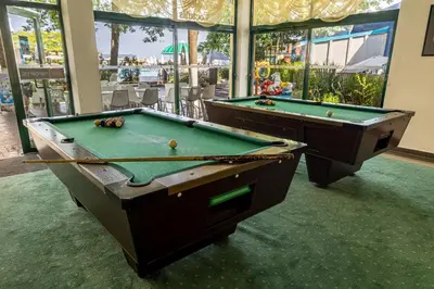 two pool tables sitting in a room with windows at Hotel Slavyanski in Sunny Beach