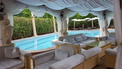 a swimming pool with couches and a blue curtain at Family Hotel Gold Pearl in Sunny Beach