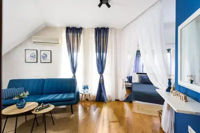 a living room with a blue couch and curtains at Sunrise Hotel in Primorsko
