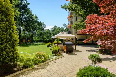 a patio with a table and an umbrella in a garden at Sunrise Hotel in Primorsko