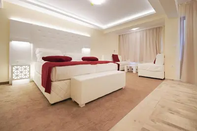 a white bedroom with a large bed and a living room at Hotel Perla Beach Luxury - All Inclusive & Free Beach Access in Primorsko