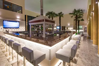 a bar in a hotel lobby with white chairs at Hotel Perla Beach Luxury - All Inclusive & Free Beach Access in Primorsko