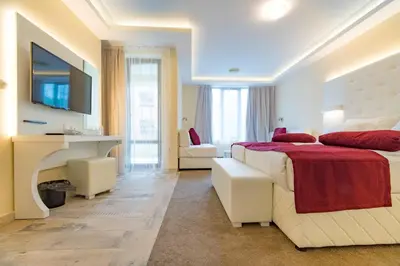 a bedroom with a bed and a desk and a television at Hotel Perla Beach Luxury - All Inclusive & Free Beach Access in Primorsko