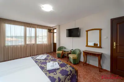 a hotel room with a bed and a mirror at Hotel Chuchulev in Sozopol