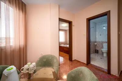 a room with a bathroom with a toilet and a table and chairs at Hotel Chuchulev in Sozopol