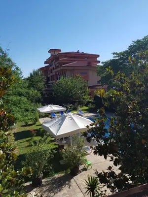 a patio with umbrellas in front of a building at Family Hotel Magnolia, Sunny Beach in Sunny Beach