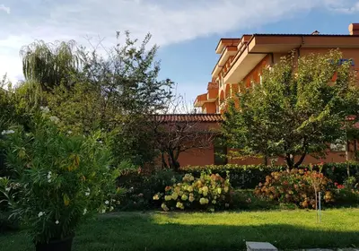 a building with trees and flowers in a yard at Family Hotel Magnolia, Sunny Beach in Sunny Beach