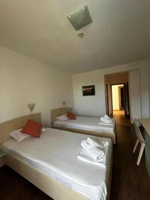 two beds in a room with white sheets and red pillows at Family Hotel Magnolia, Sunny Beach in Sunny Beach