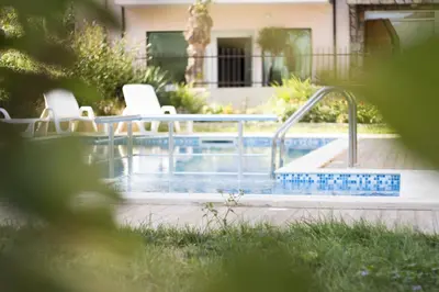 a swimming pool with two white chairs next to it at Hotel Milan in Primorsko