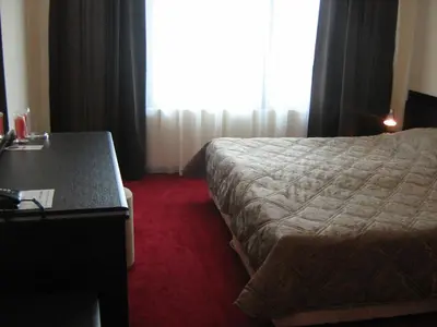 a hotel room with a bed and a desk and a window at Hotel Caesars Palace in Sunny Beach