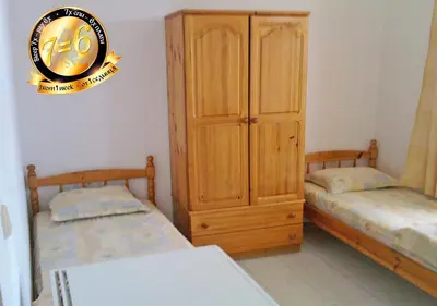 a bedroom with two beds and a wooden cabinet at Pension Dicev in Obzor