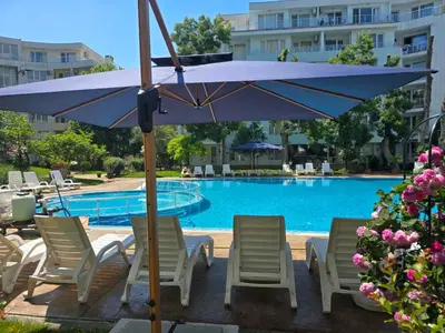 a blue umbrella and chairs next to a swimming pool at Yassen Holiday Village in Sunny Beach