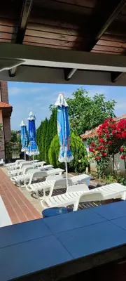 a group of lounge chairs and umbrellas on a patio at Guest House Palazzo in Byala